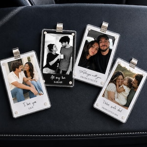 May include: Four rectangular acrylic photo frames with silver metal clips, each displaying a different black and white or colour photograph of couples and families, featuring printed text including I love you, All my love, Always with you, and Drive safe dad.