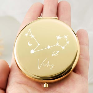 Peut inclure: Miroir compact doré avec un motif de constellation blanche et le nom "Vicky" gravé sur le devant.