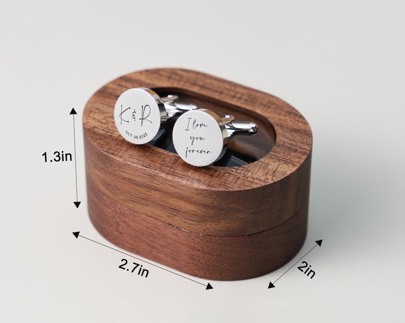 May include: A pair of silver cufflinks with the words "I love you forever" and initials engraved on them, presented in a dark wooden oval box. The box measures 2.7 inches long, 2 inches wide, and 1.3 inches high.