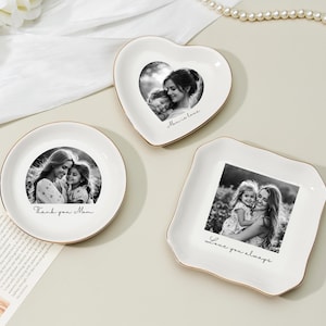 May include: Three white ceramic trinket dishes in round, heart, and square shapes, each with a gold rim. The dishes feature black and white photos and handwritten text: "Thank you Mom," "Mom is love," and "Love you always."