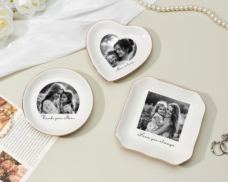 May include: Three white ceramic trinket dishes in round, heart, and square shapes, each with a gold rim. The dishes feature black and white photos and handwritten text: "Thank you Mom," "Mom is love," and "Love you always."