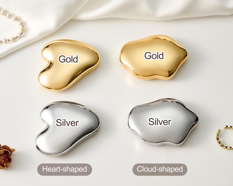 May include: Four metallic facial massage tools, two gold and two silver. The gold tools are heart-shaped and cloud-shaped. The silver tools are also heart-shaped and cloud-shaped. Each tool has the color name printed on it.