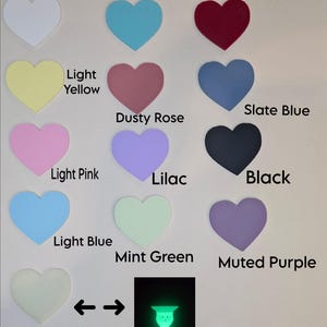 May include: A collection of heart-shaped cutouts in various colors, including white, turquoise, red, light yellow, dusty rose, slate blue, light pink, lilac, black, light blue, mint green, and muted purple. The text labels each color. A glow-in-the-dark heart is also shown.