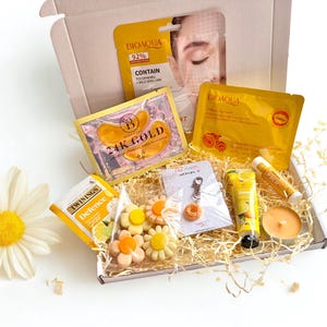 Può includere: Una confezione regalo piena di prodotti di bellezza, tra cui maschere per il viso, patch per gli occhi, balsamo per le labbra e una piccola candela. La scatola contiene anche saponi a forma di fiore, un portachiavi e una bustina di tè.