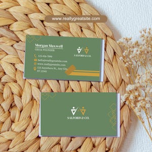 Puede incluir: Una tarjeta de visita verde con detalles dorados que presenta el texto "SALFORD & CO." y un logotipo estilizado de dos figuras. La tarjeta tambi&eacute;n incluye el texto "www.reallygreatsite.com".