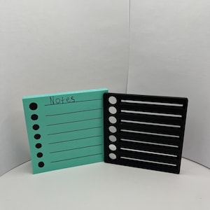 May include: A teal notepad with the word "Notes" written on it and a black plastic organizer with eight slots and circles on the side.