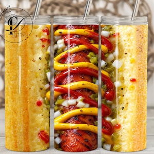May include: A cylindrical tumbler with a clear lid and a metal straw, featuring a full-wrap graphic of a hot dog in a bun topped with yellow mustard, red ketchup, diced white onions, and green relish, with a logo in the upper left corner.