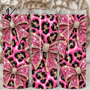 May include: Three cylindrical tumblers with clear lids and metal straws, featuring a vibrant pink and black leopard print pattern decorated with large, glittery pink bows that have sparkling rhinestone-like centers and edges throughout the design.