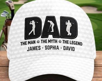May include: A white baseball cap with a textured golf ball pattern. The front features the word DAD in black, with silhouettes of golfers inside each letter. Below, the text reads THE MAN, THE MYTH, THE LEGEND, followed by the names JAMES, SOPHIA, DAVID.