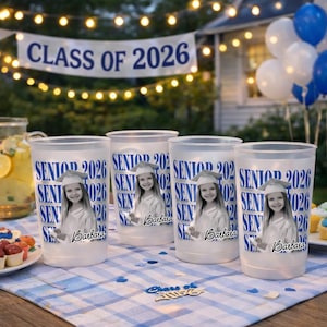 May include: Four white plastic cups with a graduation theme. Each cup has the text "SENIOR 2026" in blue, along with a photo of a graduate and the name "Barbara". A banner reads "CLASS OF 2026".