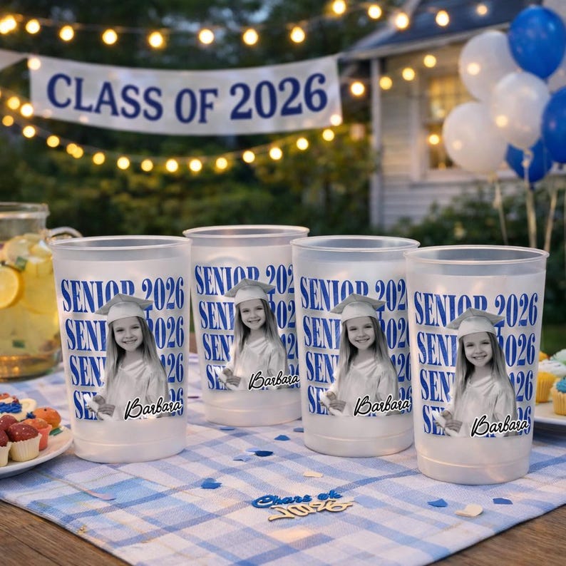 May include: Four white plastic cups with a graduation theme. Each cup has the text "SENIOR 2026" in blue, along with a photo of a graduate and the name "Barbara". A banner reads "CLASS OF 2026".
