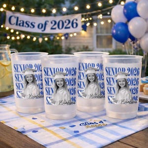 May include: Four clear plastic cups with a graduation theme. Each cup features a photo of a smiling girl in a graduation cap and gown, with the text "SENIOR 2026" and the name "Barbara". A banner reads "Class of 2026".