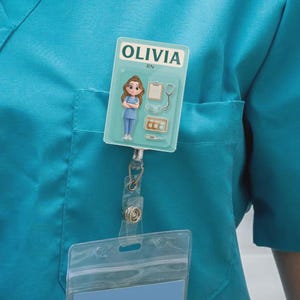 May include: A teal badge reel with the name "OLIVIA" and "RN" printed on it. The badge features a cartoon nurse figure and medical tools. The badge is attached to a teal scrub top.