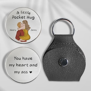 May include: Two silver pocket hug tokens with black text and illustrations. One token reads "A little Pocket Hug" with a couple hugging. The other reads "You have my heart and my ass". A black leather keychain is also included.