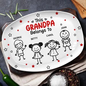 Puede incluir: Una bandeja de servir ovalada blanca con el texto en negro This GRANDPA Belongs to, acompañada de cuatro ilustraciones de líneas negras de niños etiquetados como George, Betty, Carol y John, decorada con pequeños motivos de estrellas rojas y negras.