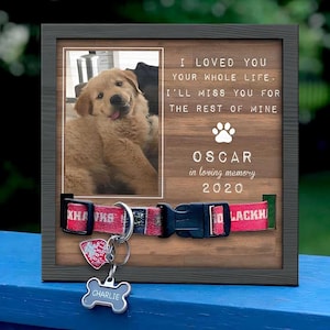 May include: A wooden memorial frame with a photo of a golden retriever puppy. The frame has a collar and dog tag attached. The text on the frame reads "I loved you your whole life. I'll miss you for the rest of mine. Oscar in loving memory 2020". The dog tag reads "Charlie".