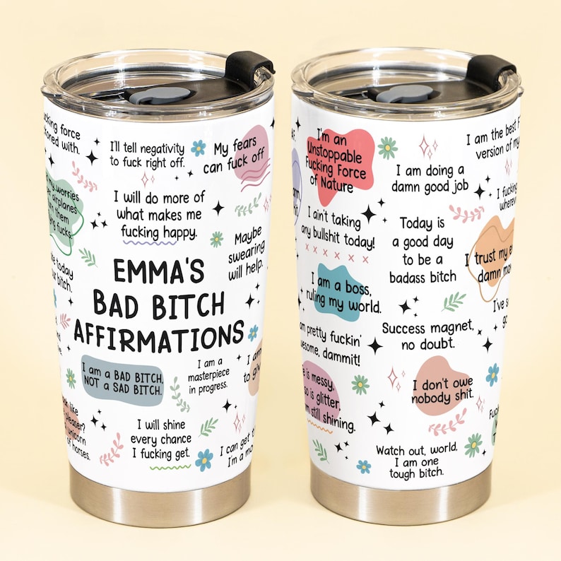 May include: A white stainless steel tumbler with a black lid. The tumbler is covered in colorful affirmations and the text "EMMA'S BAD BITCH AFFIRMATIONS". The design includes floral and star accents.