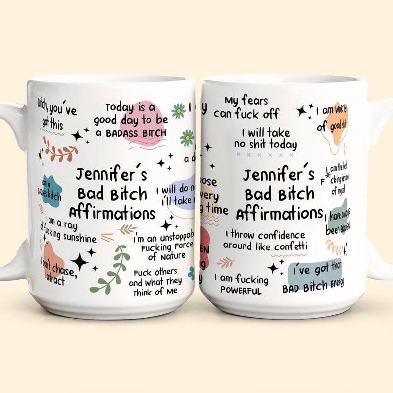 May include: Two white ceramic mugs with black text and colorful accents. The mugs feature affirmations, including "Jennifer's Bad Bitch Affirmations" and phrases like "I'm an unstoppable fucking force of nature."