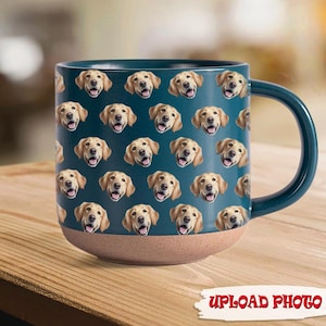 Könnte beinhalten: Eine türkisfarbene Keramiktasse mit einem sich wiederholenden Muster aus Golden Retriever-Gesichtern. Die Tasse hat einen braunen Boden und einen türkisfarbenen Henkel. Die Worte "UPLOAD PHOTO" sind unten rot aufgedruckt.