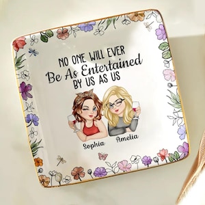 Può includere: Piatto da portata quadrato in ceramica con bordo floreale e finiture dorate. Il piatto presenta un'illustrazione di due donne che tengono calici di vino, con la scritta "NO ONE WILL EVER BE AS ENTERTAINED BY US AS US".