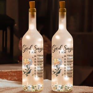 Peut inclure: Deux bouteilles décoratives en verre avec bouchons en liège, éclairées par des lumières internes. Chaque bouteille porte l'inscription "God Says I AM" et un motif floral. Les bouteilles sont décorées de mots inspirants.