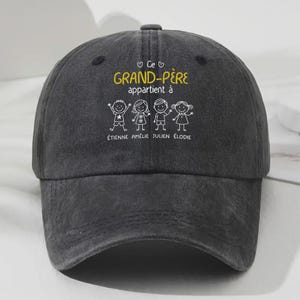 May include: A dark gray baseball cap with the text "Ce Grand-Père appartient à" in yellow and white. Below the text are stick figures of children and their names: Étienne, Amélie, Julien, and Élodie.