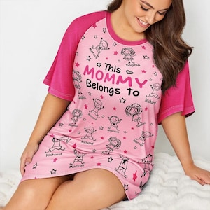 May include: Pink nightgown with short sleeves and a round neckline. The nightgown features a pattern of cartoon figures, stars, and the text "This MOMMY Belongs To". The sleeves are a darker pink.