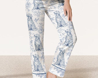 May include: White pajama pants featuring a blue toile-style print of sitting golden retriever dogs and floral patterns. The pants have a straight-leg cut with a blue piped hem detail at the bottom of each leg and a matching white button-up top.