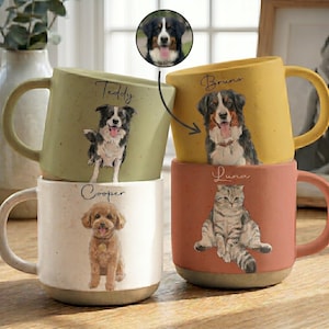 Può includere: Tre tazze in ceramica con finitura maculata in verde salvia, crema e giallo senape, più una tazza color terracotta. Ognuna presenta il ritratto di un animale domestico e un nome: Teddy, Bruno, Cooper e Luna. Un inserto circolare mostra un bovaro del bernese.