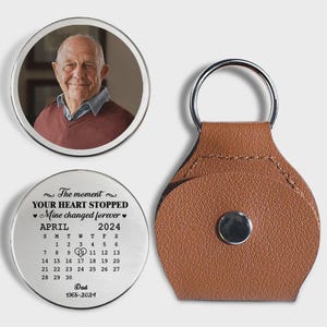 May include: A personalized keychain set featuring a photo and a calendar. The photo is of an older man in a maroon sweater. The calendar shows April 2024 with a heart on the 10th. The keychain has a brown leather backing.