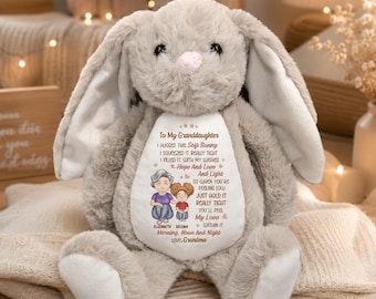 Op de afbeelding: Een grijs pluche konijn knuffeldier met lange oren en een roze neus. Het konijn heeft een wit vlak op de borst bedrukt met een illustratie van een grootmoeder en kleindochter, samen met de tekst: To My Granddaughter, I hugged this soft bunny, I squeezed it really tight, I filled it with my wishes, hope and love and light, so when you're feeling low, just hold it really tight, you'll feel my love within it, morning, noon and night, love, Grandma.