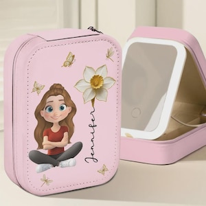 May include: Pink travel jewelry case with a cartoon illustration of a girl, a white daffodil, and the name "Jennifer". The case is open, revealing a mirror. Butterflies and dragonflies decorate the case.