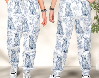 May include: White sweatpants featuring a repeating blue toile-style pattern of sitting dogs and floral motifs. The pants have an elastic waistband with a drawstring and cuffed ankles, shown from both the front and back perspectives.