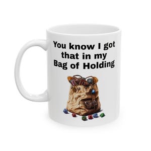 May include: White ceramic mug with a black graphic that says "You know I got that in my Bag of Holding" and a cartoon illustration of a brown bag with a blue gem and dice spilling out.