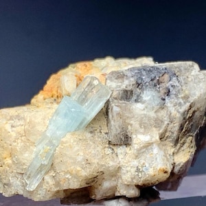 May include: A light blue aquamarine crystal specimen on a matrix of gray and white rock. The crystal is about 2 cm long and has a sharp, well-defined termination.