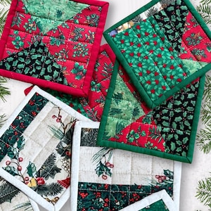 May include: A collection of quilted square Christmas-themed pot holders. The pot holders feature red, green, and black fabrics with holly and berry patterns. Some have red or green borders, and all are quilted with a square pattern.