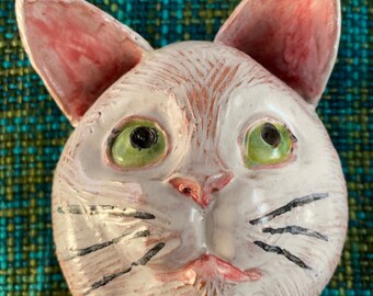 Ceramic wall art of a white cat, portrait study which is glazed with majolica glaze.