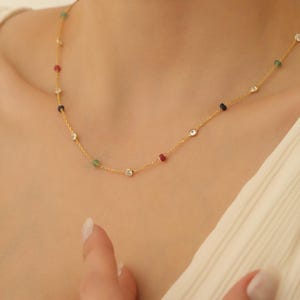 Puede incluir: Un collar de cadena de oro con pequeñas piedras preciosas de colores y piedras de circonita cúbica transparentes.