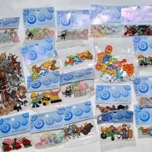 May include: A collection of assorted plastic buttons packaged in individual clear plastic bags with blue header cards. The buttons feature various shapes including animals, construction vehicles, strawberries, and fantasy characters in diverse colors.