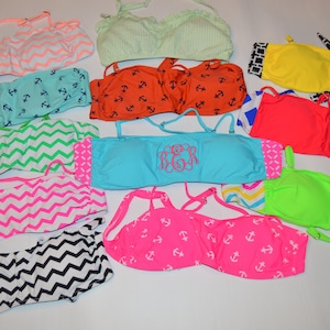 May include: A collection of colorful bikini tops in various patterns and designs. Styles include chevron, anchor prints, and solid colors like neon pink, green, and yellow. Some tops have adjustable straps and decorative details.