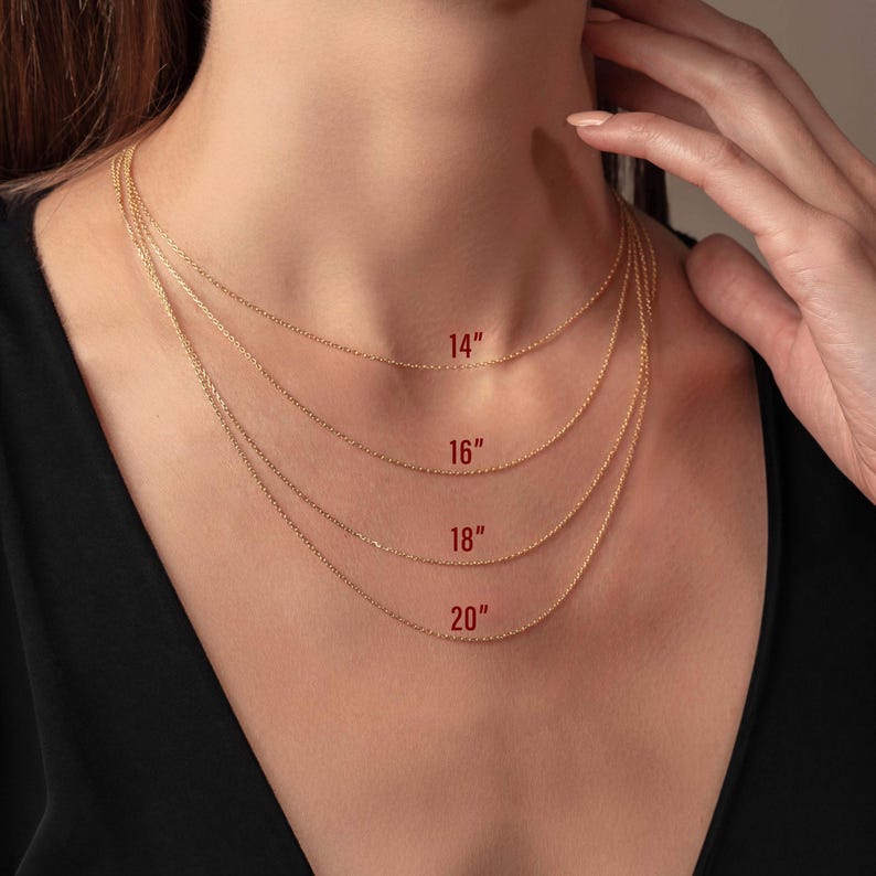 May include: Four gold-colored chain necklaces of varying lengths, displayed on a person's neck. The lengths are labeled as 14", 16", 18", and 20". The chains are delicate and appear to be made of a fine metal.