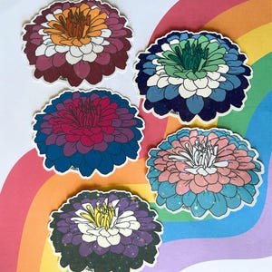 May include: Five flower stickers with white borders in various colours. The flowers feature combinations such as orange, burgundy, and white; blue, green, and white; red, blue, and purple; pink, blue, and white; and purple, yellow, and white.