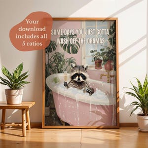 Könnte beinhalten: Gerahmter Kunstdruck mit einem Waschbären in einer rosa Badewanne voller Blasen, der ein Sektglas hält. Das Kunstwerk enthält den Text "SOME DAYS YOU JUST GOTTA WASH OFF THE DRAMAS". Umgeben von üppigen grünen Pflanzen.