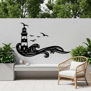 Könnte beinhalten: Schwarze Metall-Wandkunst mit einem Leuchtturm, Wellen und Möwen. Der Leuchtturm hat ein gestreiftes Design und befindet sich über stilisierten Wellen. Mehrere Möwen fliegen über dem Leuchtturm. Das Kunstwerk ist an einer weißen Wand befestigt.
