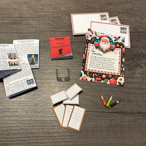 Könnte beinhalten: Eine Sammlung von Miniatur-Weihnachtsartikeln, darunter Zeitungen, ein rotes Büchlein, eine Brille, leere Karten, Bleistifte und ein Weihnachtsbrief. Der Brief ist mit festlichen Bildern verziert.