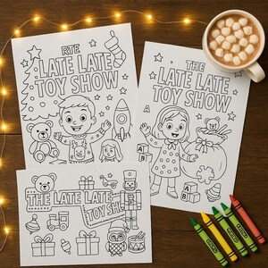 以下が含まれることがあります： 「RTE The Late Late Toy Show」と「The Late Late Toy Show」の文字が入った、白黒の塗り絵が3枚。子供、おもちゃ、お祝いの要素のイラストが描かれています。マシュマロが入ったホットチョコレートのマグカップとクレヨンも画像にあります。