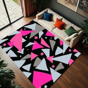 Könnte beinhalten: Ein geometrischer Teppich in Schwarzweiß mit rosa Dreiecken. Der Teppich hat ein modernes Design und ist perfekt, um jedem Raum einen Farbtupfer zu verleihen.