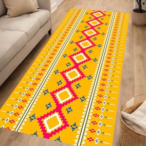 Op de afbeelding: Een rechthoekige loper met een felgele achtergrond en een centrale verticale rij van verbonden roze en witte ruitpatronen, geflankeerd door kleinere geometrische motieven in rood, wit en blauw langs de zijranden.
