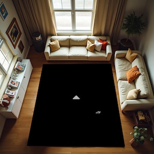 May include: A black area rug with a white triangle and a small white symbol in the centre. The rug is on a wooden floor in a living room with two white sofas and a brown couch.
