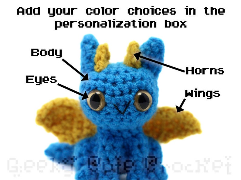 May include: A crocheted blue dragon with yellow wings and horns. The dragon has black eyes and a white mouth.